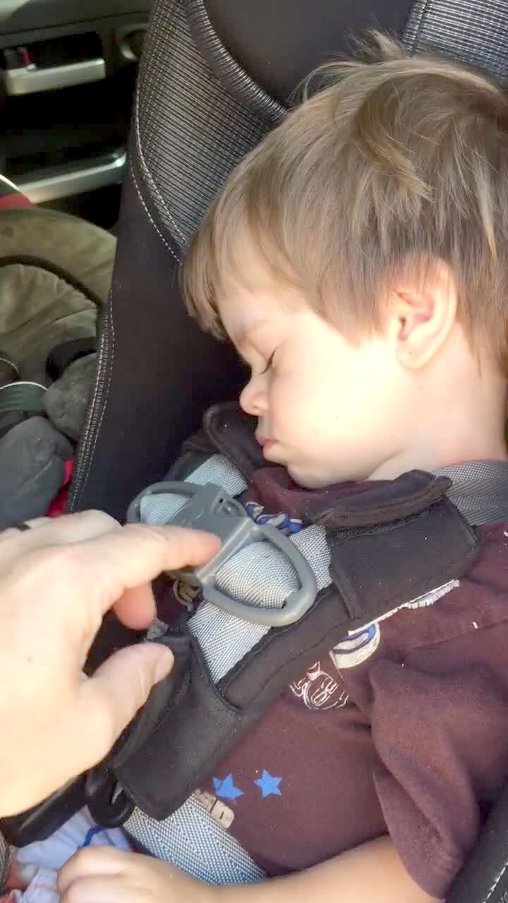 Video thumbnail showing: A sleeping tot boy buckles his seat belt each time the camera holder unbuckles it.