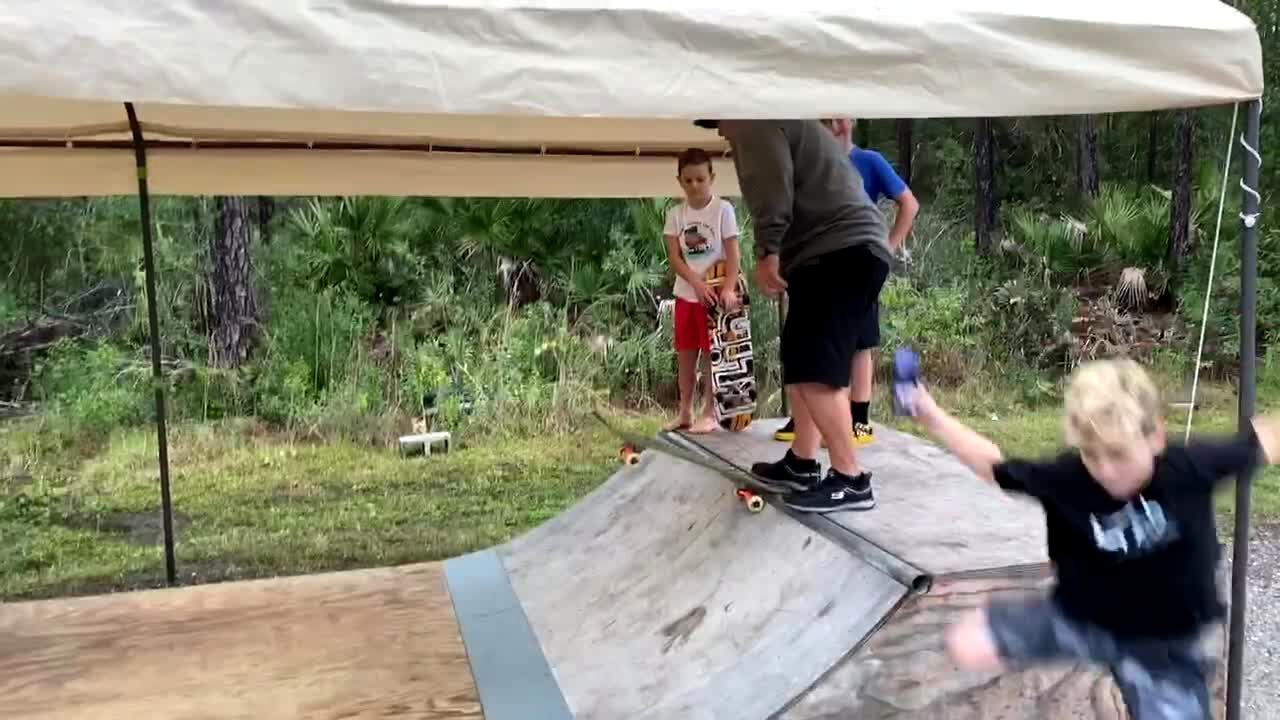 Video thumbnail showing: A man rides on a skateboard down a ramp in the backyard and falls flat on his back.